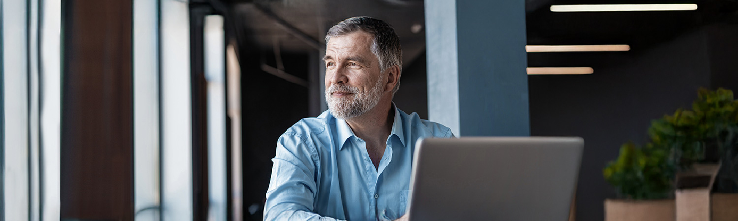 Man working on his laptop starring out the window